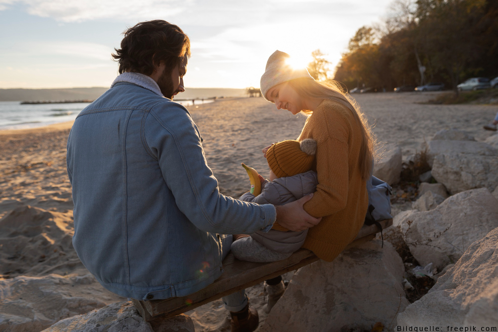 Liebevolle Eltern-Kind-Beziehung Eltern haben einen liebevollen Moment mit ihrem Kleinkind am Strand